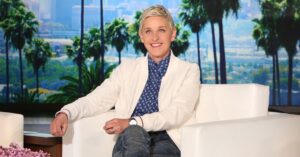 Photo showing Ellen DeGeneres wearing a white blazer and blue polka dot button-up shirt.