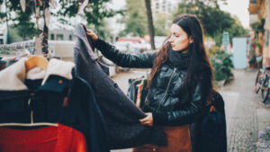 Photo shows a person shopping at an outdoor clothing market in Kreuzberg, Berlin, wearing a black leather jacket. Can you still be an ethical vegan if you go thrifting for wool and leather?