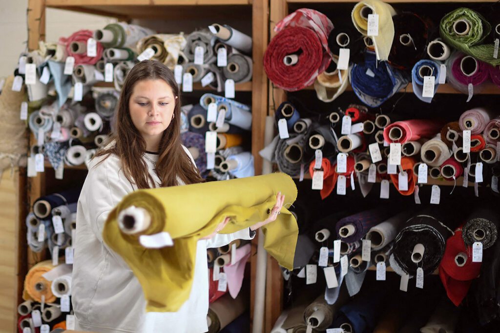 Photo shows a young woman holding a large roll of fabric. But what is deadstock?