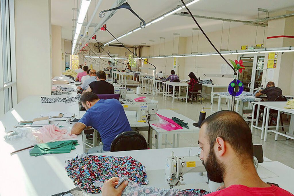 Photo shows a room full of workers sewing clothing.